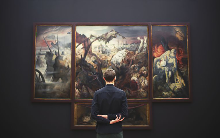 man looking at art hanging on a wall